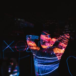 A person stretching their back with neon light accents.